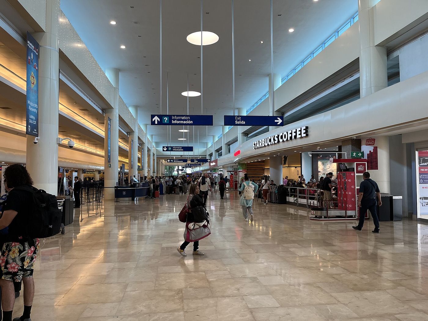 Travelers with suitcases walking out of the arrivals doors at Cancun International Airport