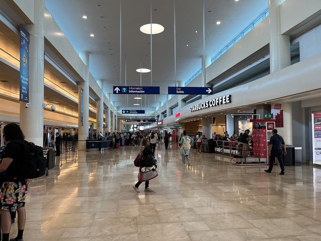 Travelers with suitcases walking out of the arrivals doors at Cancun International Airport